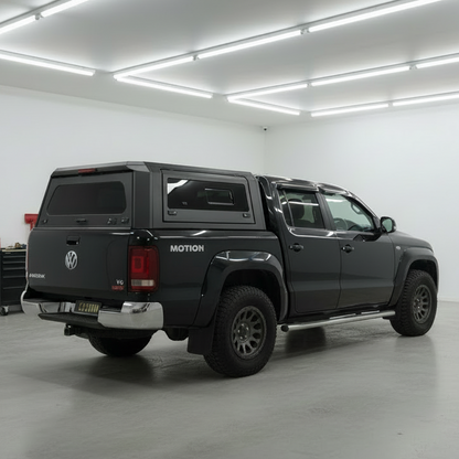 Black Volkswagen Amarok with custom canopies' modular ute canopy and a roof rack in a garage setting