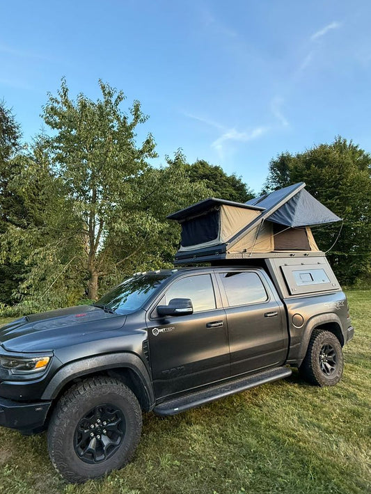 Black SUV with a rooftop tent parked on grass with trees in the background aluminium ute tub canopy